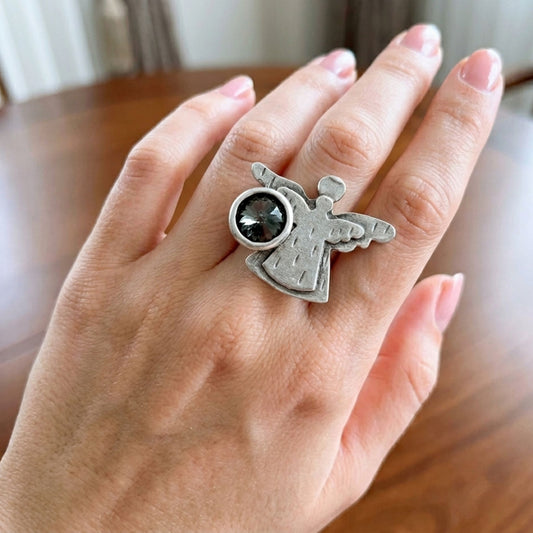 Modelo luciendo anillo Zamak ángel 3D con circonita gris ajustable, diseño espiritual celestial plateado, Joyería Osnor Zamak