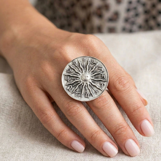Modelo luciendo anillo Zamak zodíaco con sol y 12 signos en relieve ajustable, diseño espiritual exclusivo plateado envejecido, Joyería Osnor Zamak