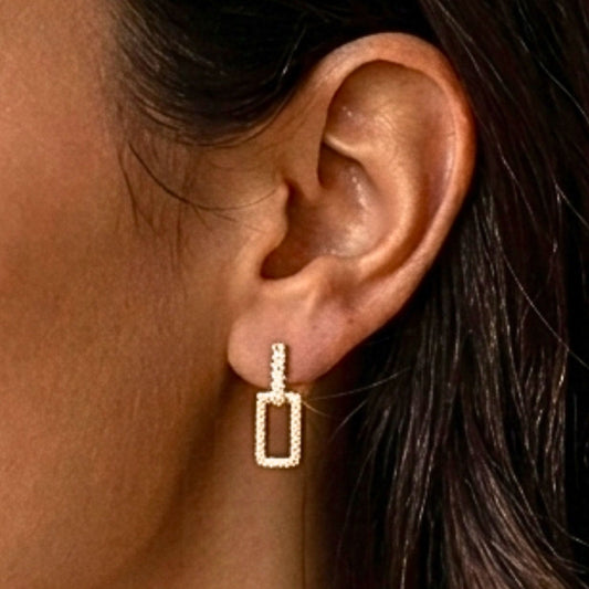 Chica luciendo Pendientes acero inoxidable dorado chapado oro 14ktes diseño joyería osnor