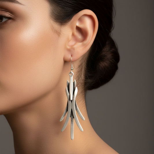 Mujer con pendientes largos zamak plateados de diseño escultural - Joyería Osnor Zamak