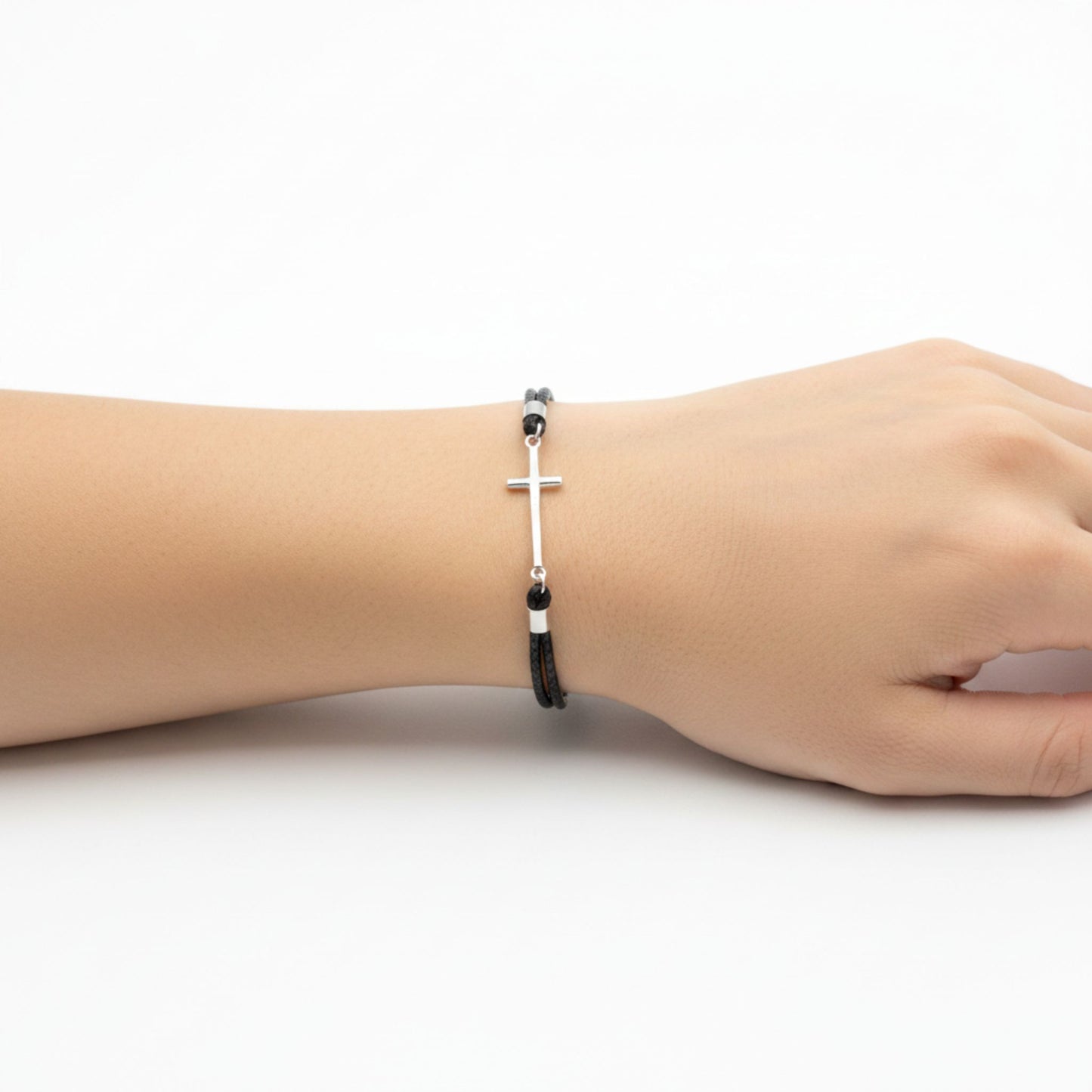 Mujer Luciendo Pulsera Cordón Negro Trenzado con Cruz de Plata Rodio. Joyeria Osnor