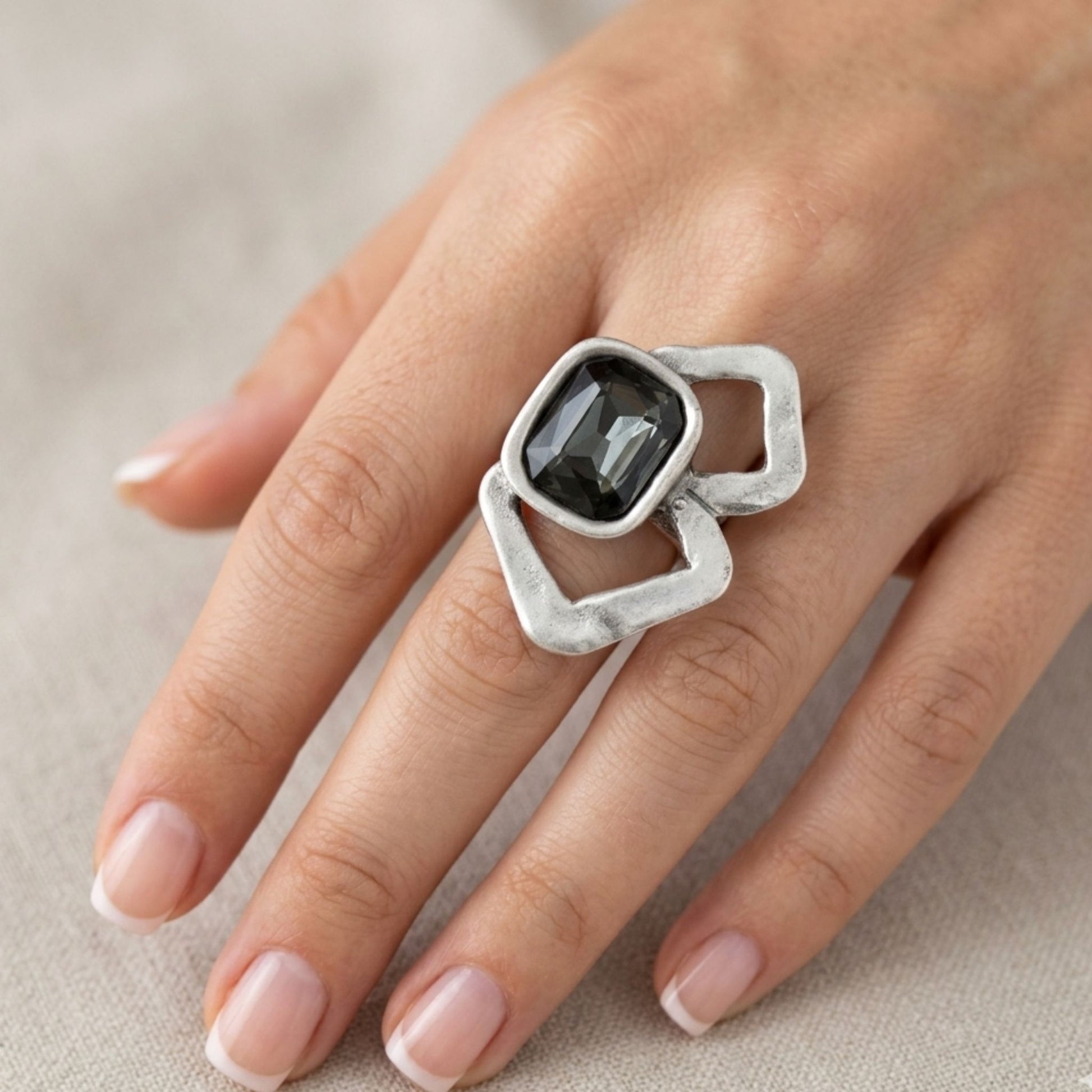 Modelo luciendo anillo Zamak circonita gris cushion-cut con aro ajustable, diseño statement glamour plateado, Joyería Osnor Zamak
