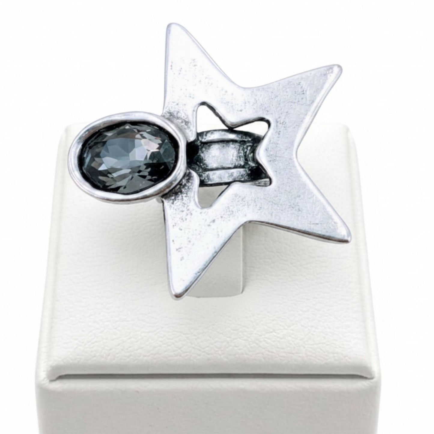 Anillo Zamak estrella 6 puntas con circonita gris ovalada sobre expositor de madera, Joyería Osnor Zamak