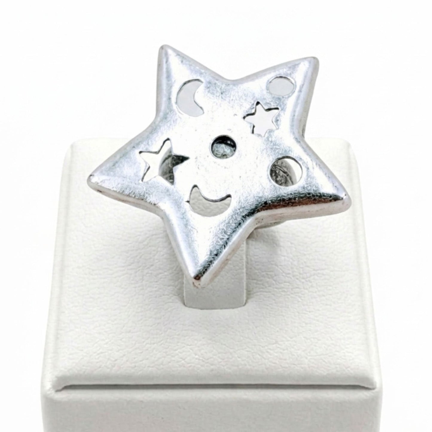 Anillo Zamak mujer estrella plateado con calados de luna y círculos sobre expositor de madera, Joyería Osnor Zamak