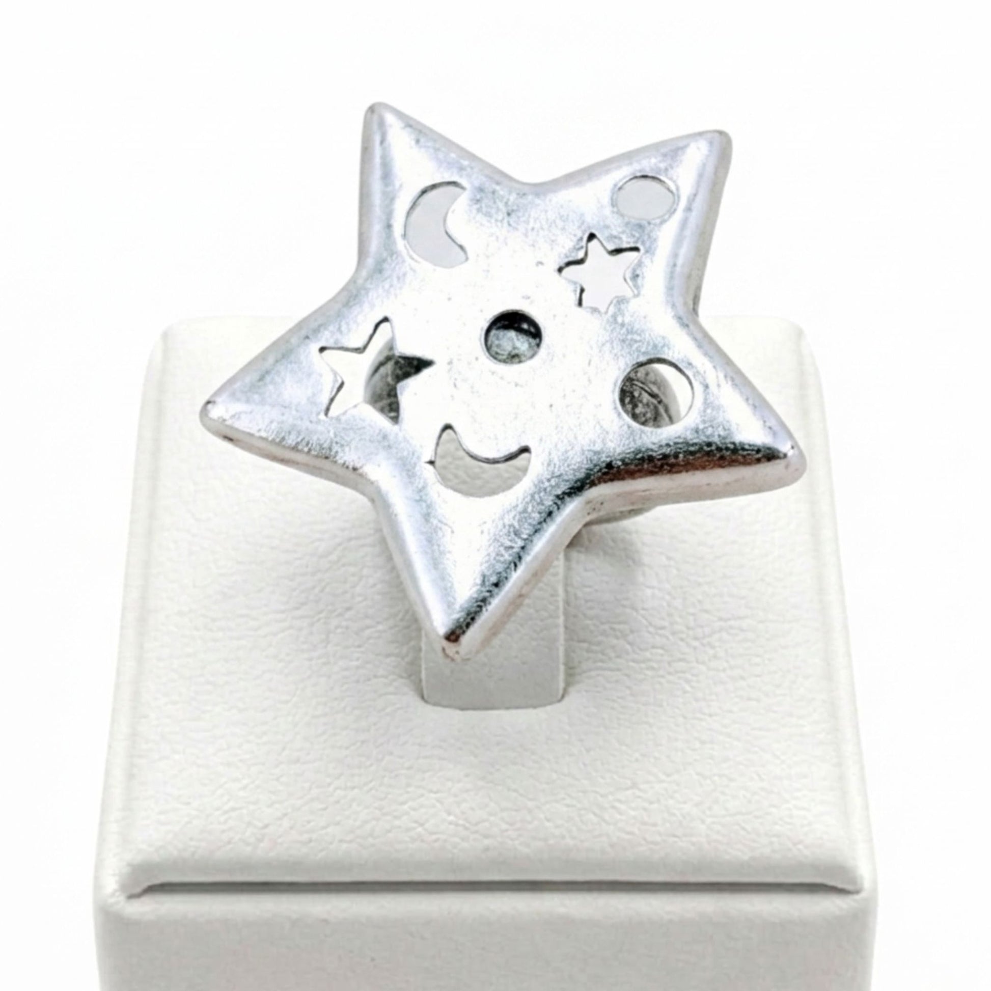 Anillo Zamak mujer estrella plateado con calados de luna y círculos sobre expositor de madera, Joyería Osnor Zamak
