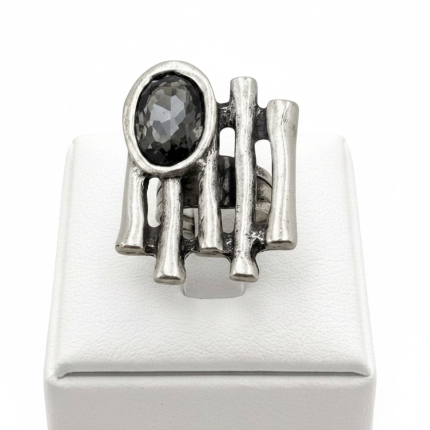 Anillo Zamak con circonita gris oscuro oval con varillas sobre expositor de madera, Joyería Osnor Zamak