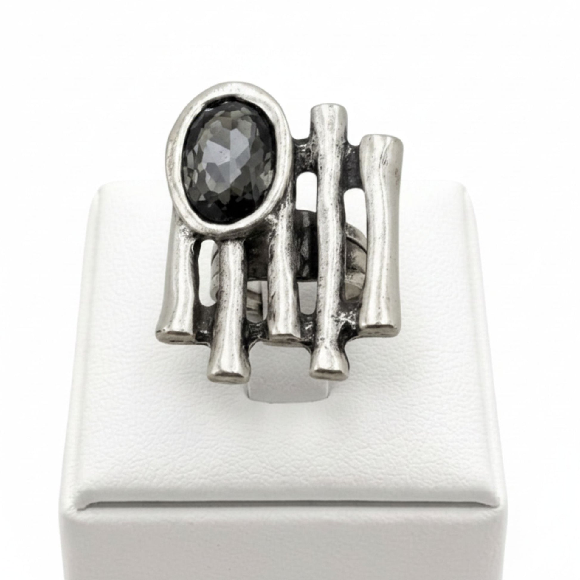 Anillo Zamak con circonita gris oscuro oval con varillas sobre expositor de madera, Joyería Osnor Zamak