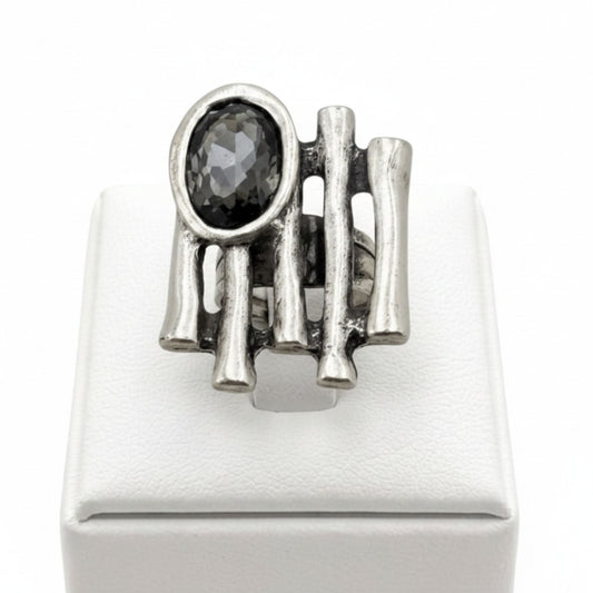 Anillo Zamak con circonita gris oscuro oval con varillas sobre expositor de madera, Joyería Osnor Zamak