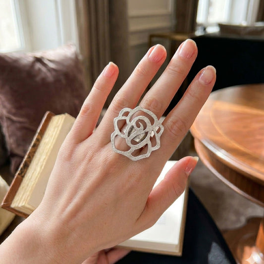 Modelo luciendo anillo Zamak rosa calada en filigrana ajustable, diseño floral romántico plateado, Joyería Osnor Zamak