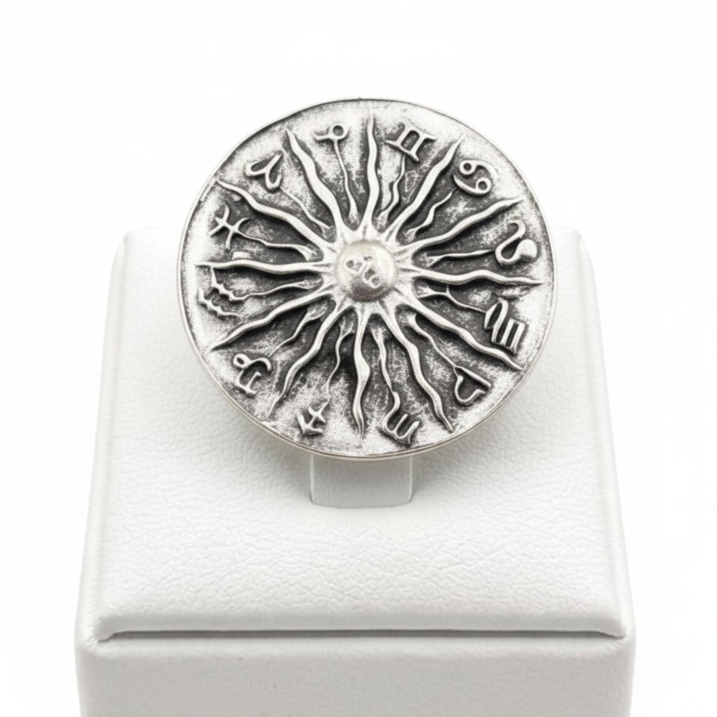 Anillo Zamak ajustable con los 12 signos del zodíaco y sol central en relieve sobre expositor de madera,  Joyería Osnor Zamak