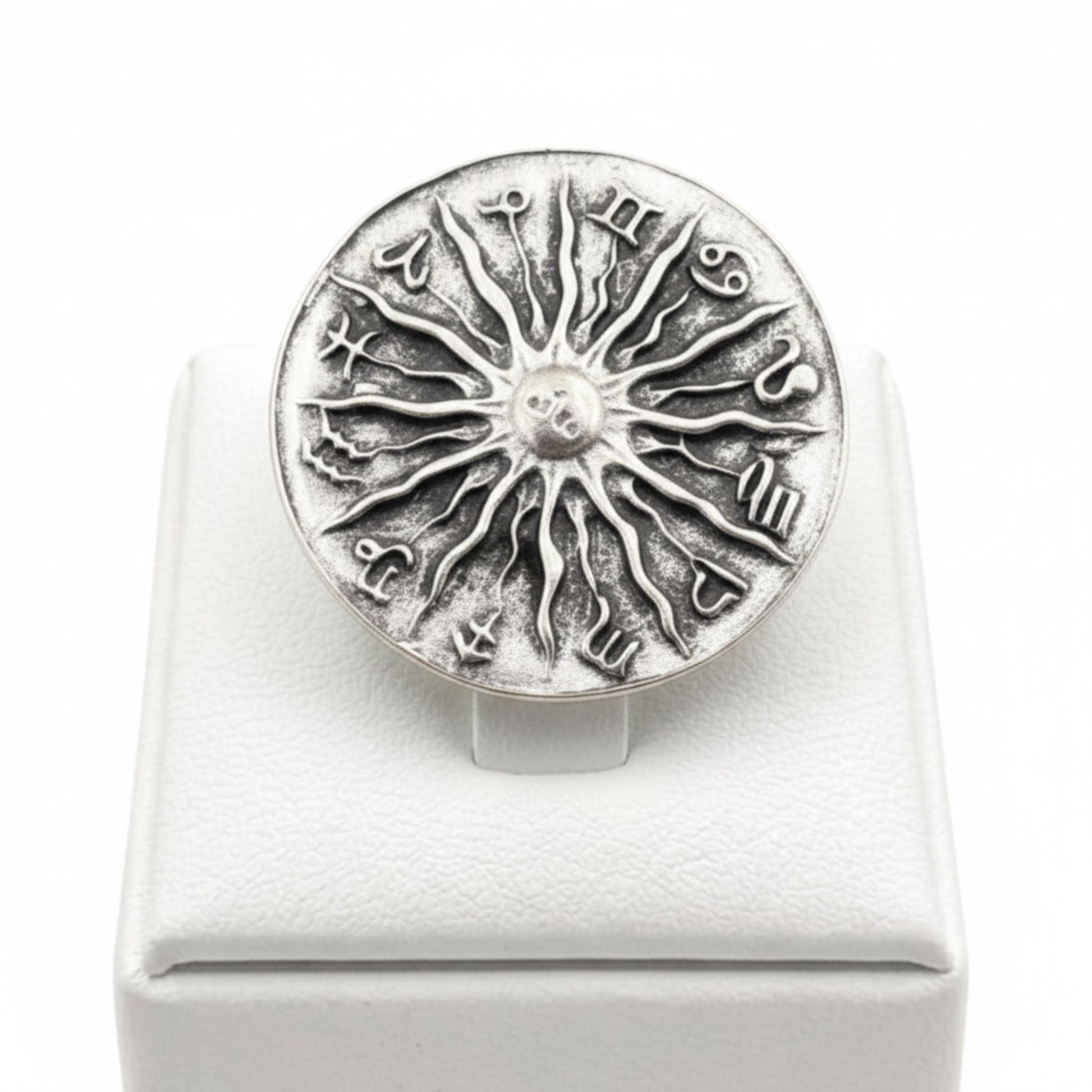 Anillo Zamak ajustable con los 12 signos del zodíaco y sol central en relieve sobre expositor de madera,  Joyería Osnor Zamak