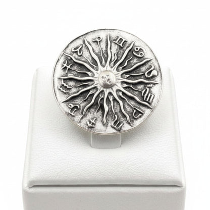 Anillo Zamak ajustable con los 12 signos del zodíaco y sol central en relieve sobre expositor de madera,  Joyería Osnor Zamak
