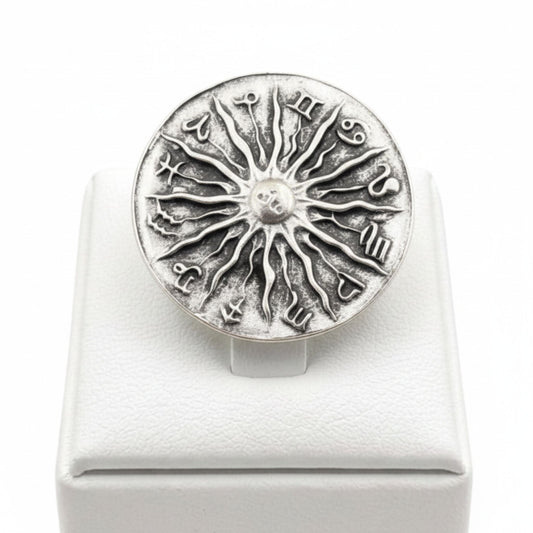  Anillo Zamak ajustable con los 12 signos del zodíaco y sol central en relieve sobre expositor de madera,  Joyería Osnor Zamak
