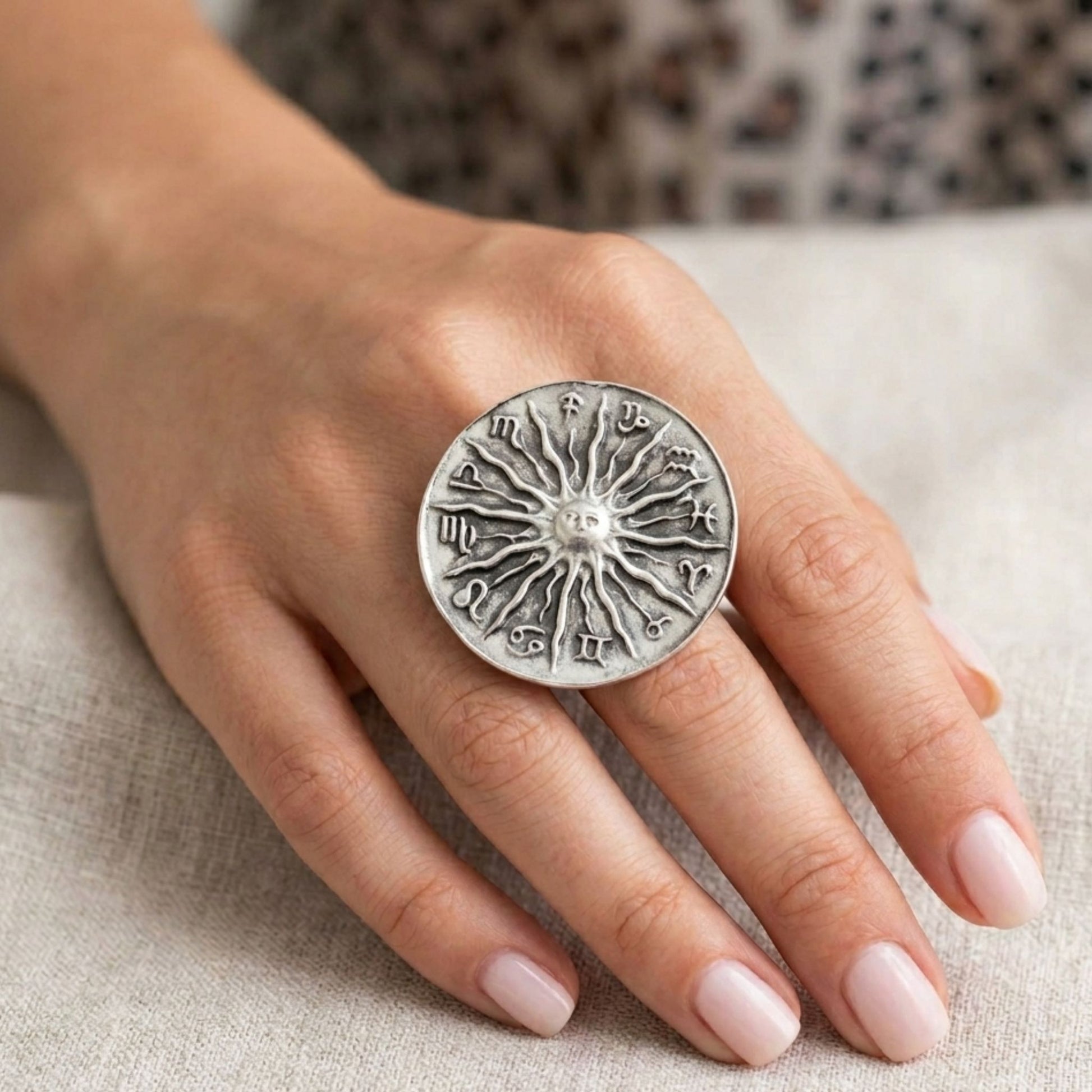 Modelo luciendo anillo Zamak zodíaco con sol y 12 signos en relieve ajustable, diseño espiritual exclusivo plateado envejecido, Joyería Osnor Zamak