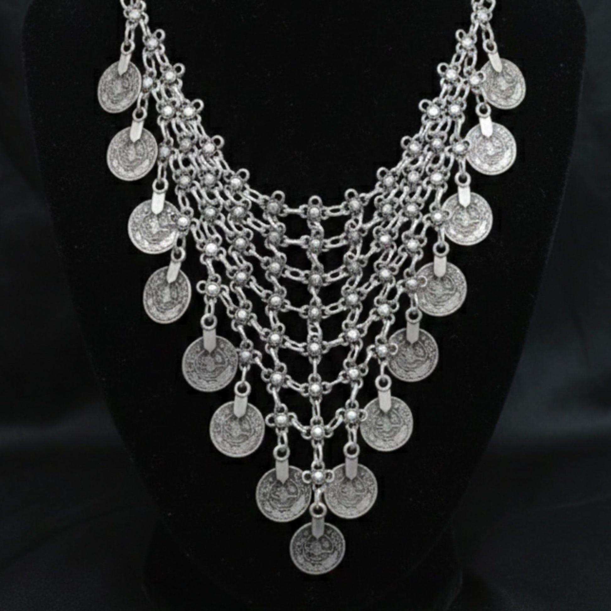 Collar de zamak hipoalergénico con monedas sobre fondo negro - vista frontal completa mostrando diseño en cascada
