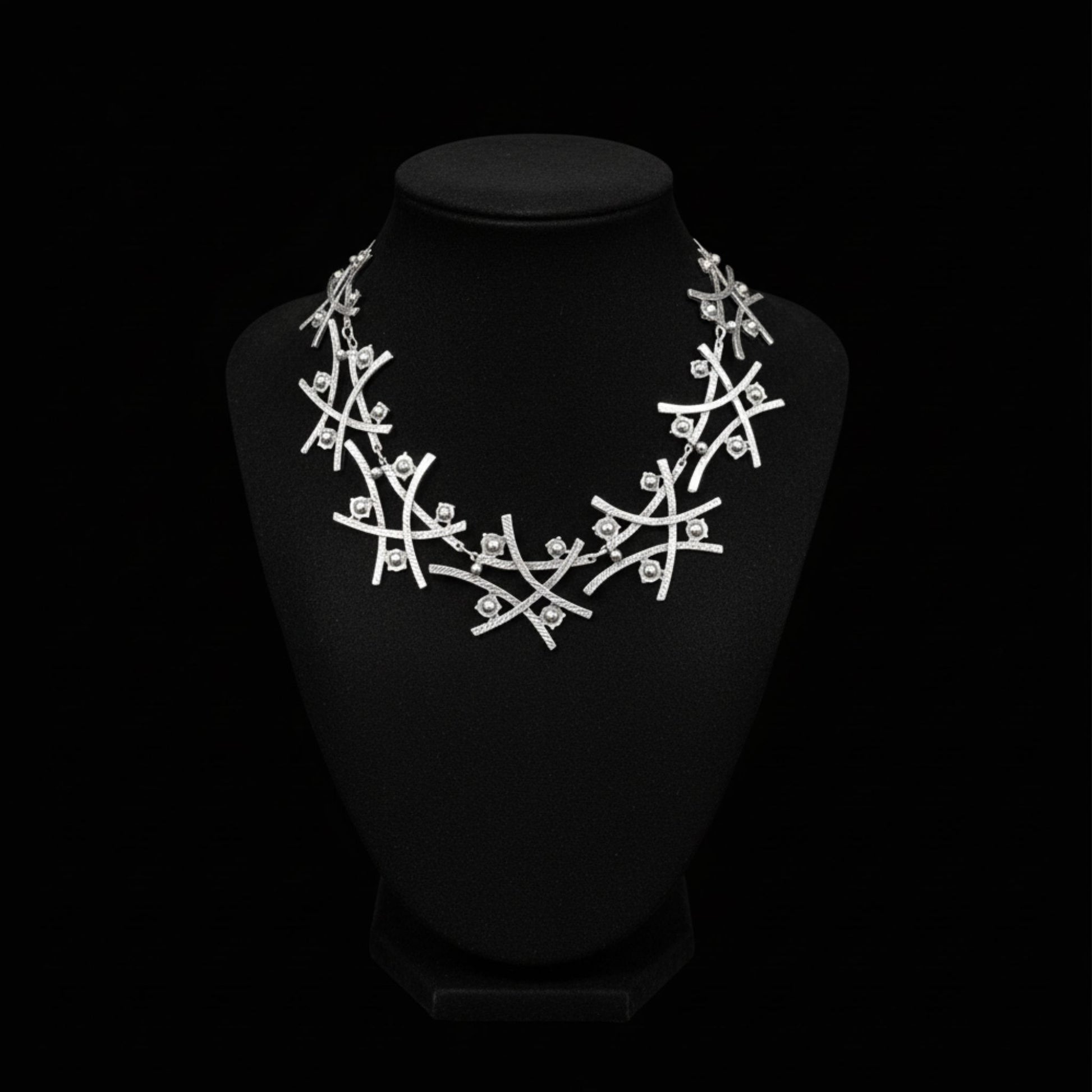 Collar de zamak plateado con diseño de ramas entrelazadas y detalles esféricos
