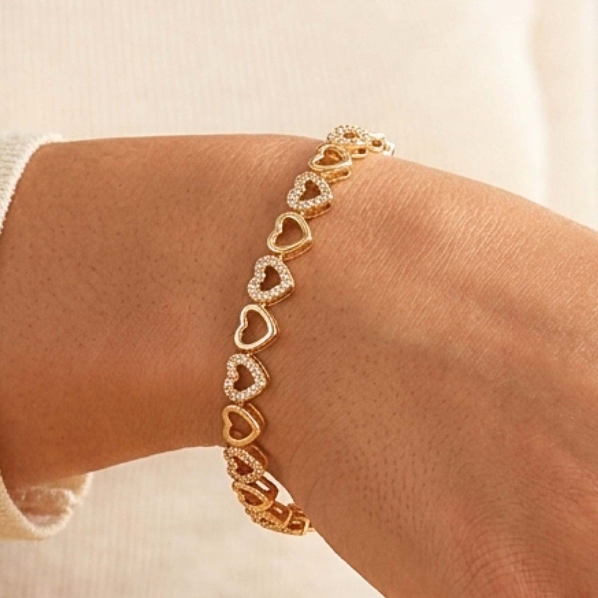 Chica luciendo pulsera de acero inoxidable dorado chapado oro 14ktes circonitas blancas engastadas diseño joyería osnor corazón 