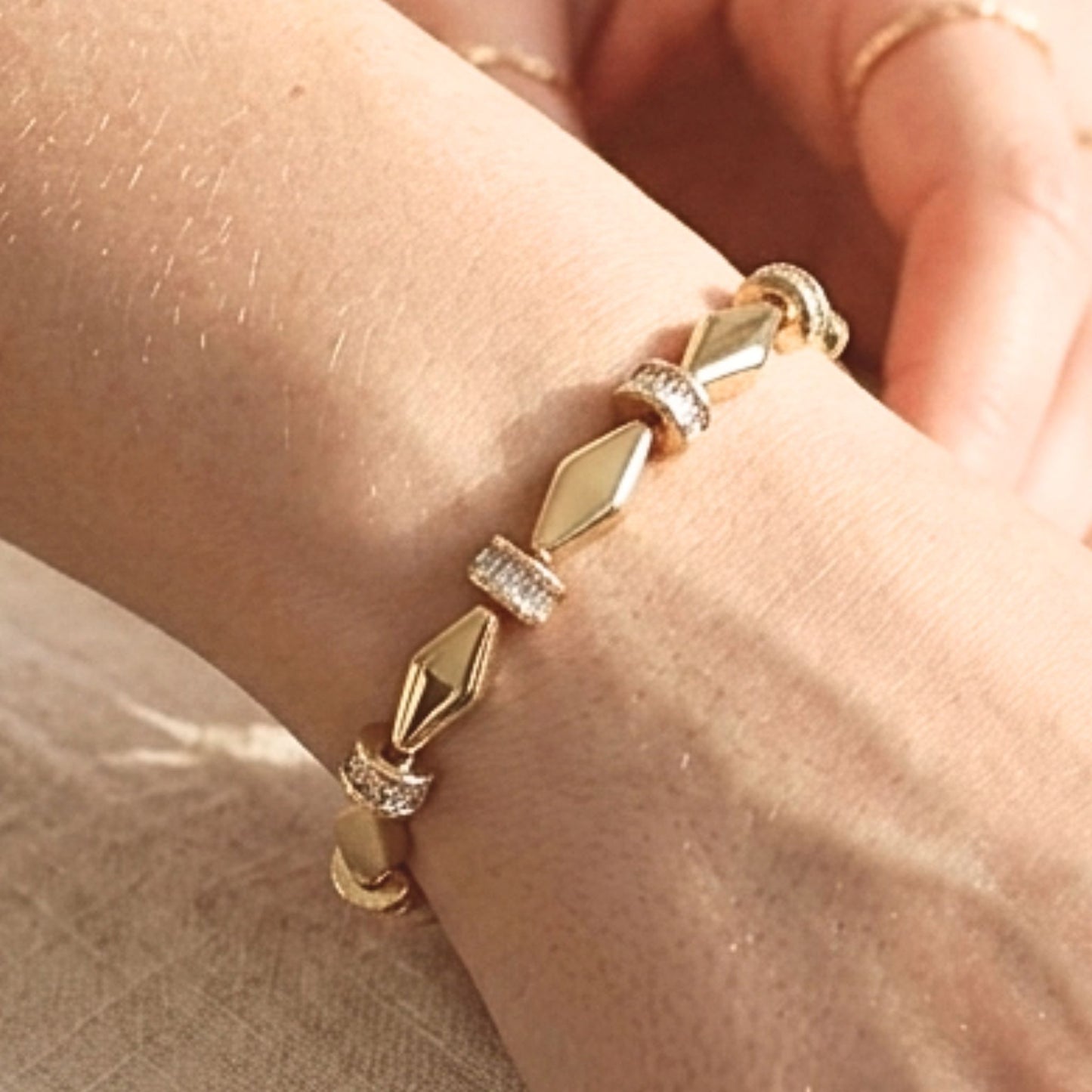 Chica luciendo pulsera de acero inoxidable dorado chapado oro 14ktes circonitas blancas engastadas diseño joyería osnor moda 