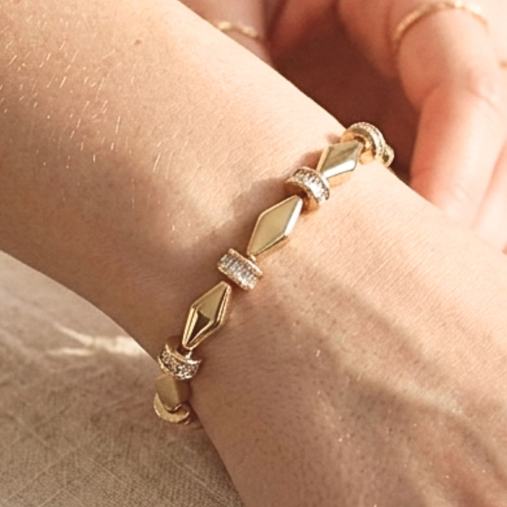Chica luciendo pulsera de acero inoxidable dorado chapado oro 14ktes circonitas blancas engastadas diseño joyería osnor moda 
