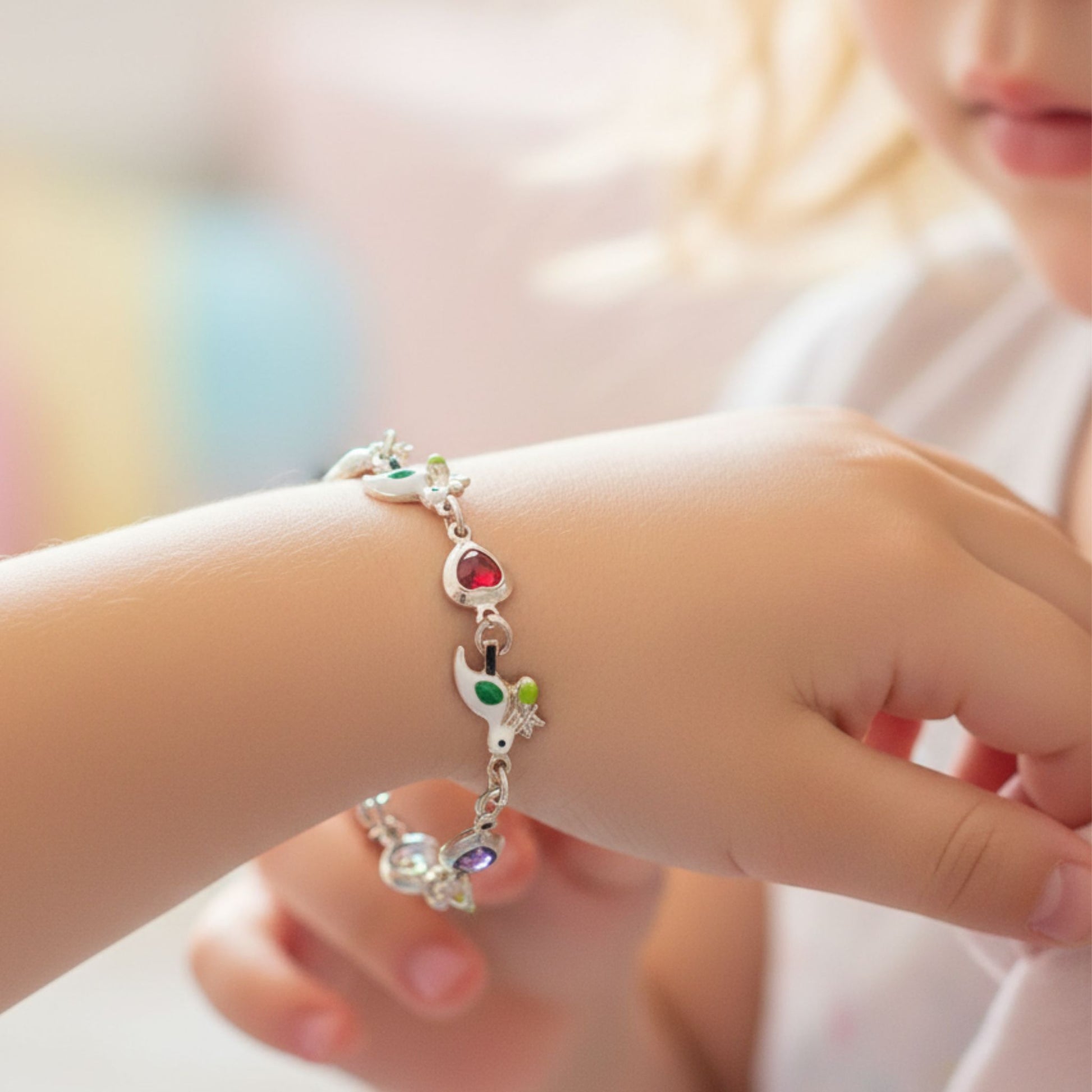 Niña Luciendo Pulsera Infantil Plata Pajaritos Esmalte y Corazones de Colores. Joyeria Osnor