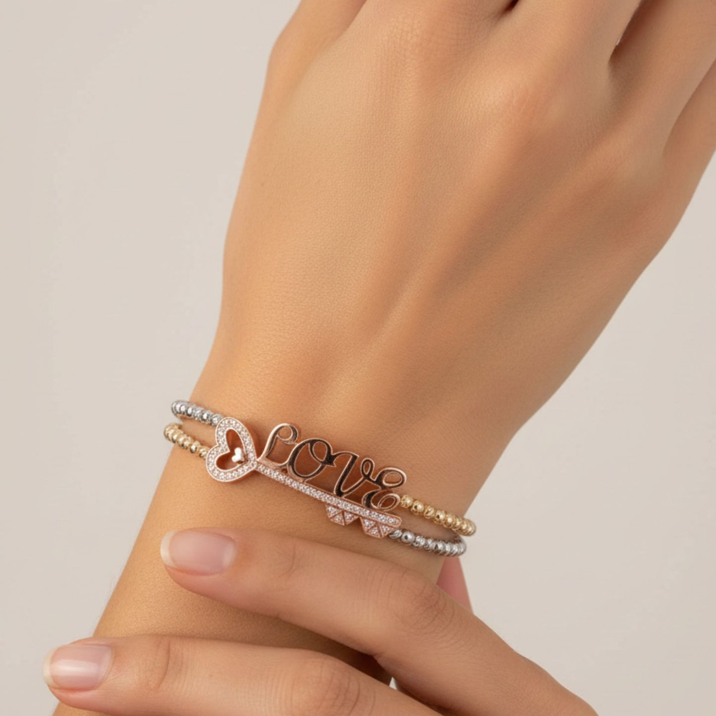 Mujer Luciendo Pulsera Doble Cadena de Bolas "LOVE" en Plata con Baño de Oro Amarillo y Oro Rosa. Joyeria Osnor