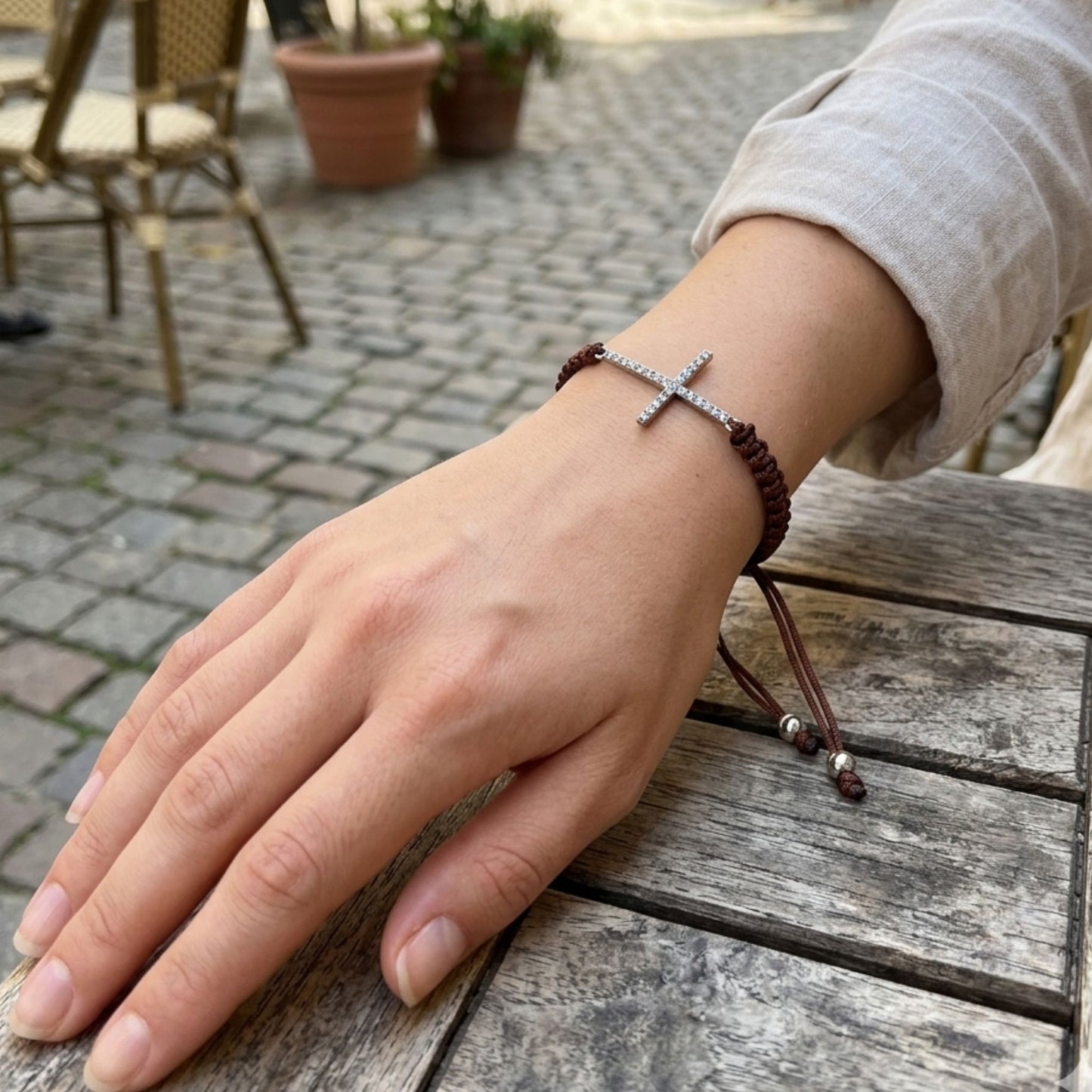 Mujer Luciendo Pulsera Macramé Marrón con Cruz de Plata Rodio y Circonitas. Joyeria Osnor