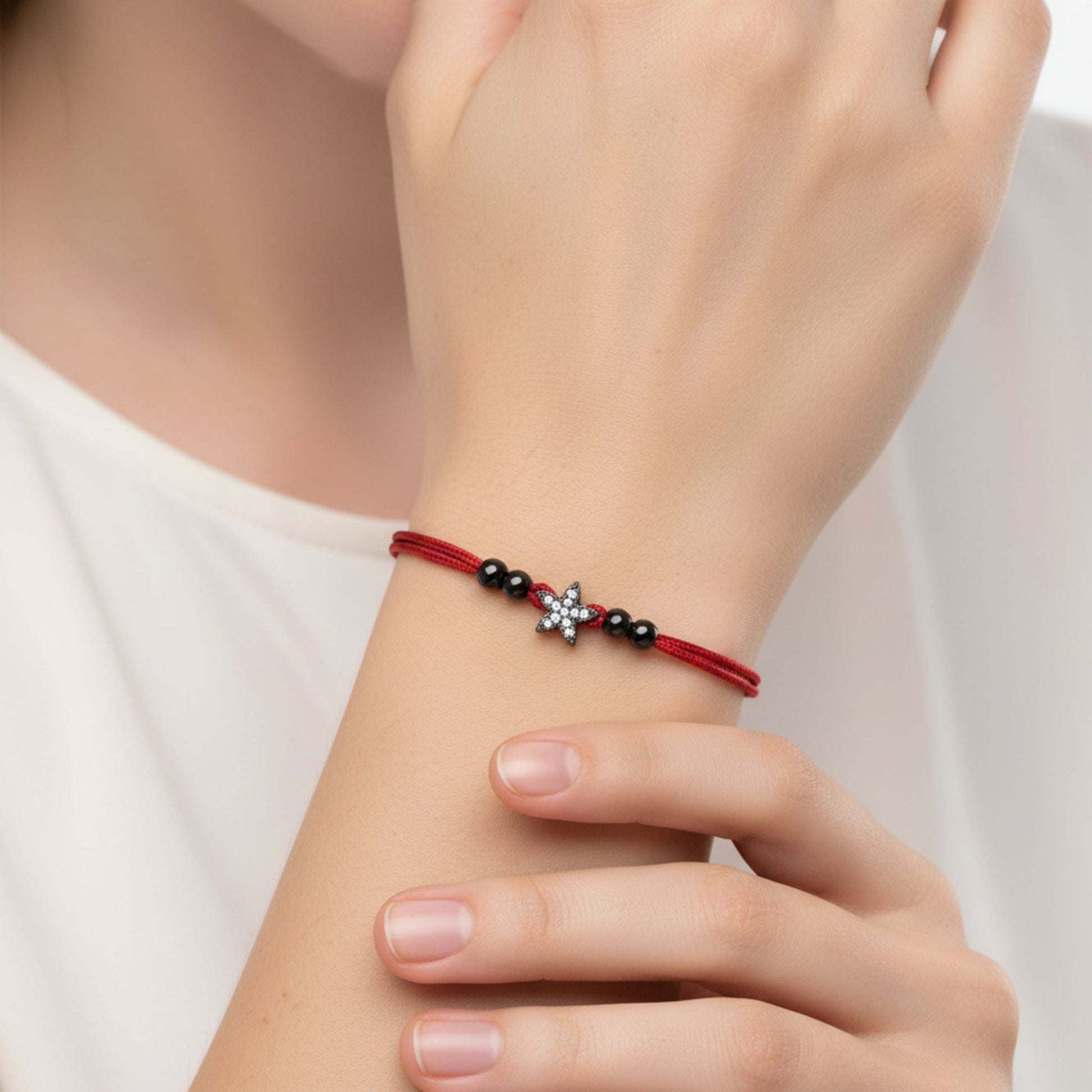Mujer Luciendo Pulsera de Hilo Rojo Doble con Estrella de Plata y Rutenio Negro. Joyeria Osnor