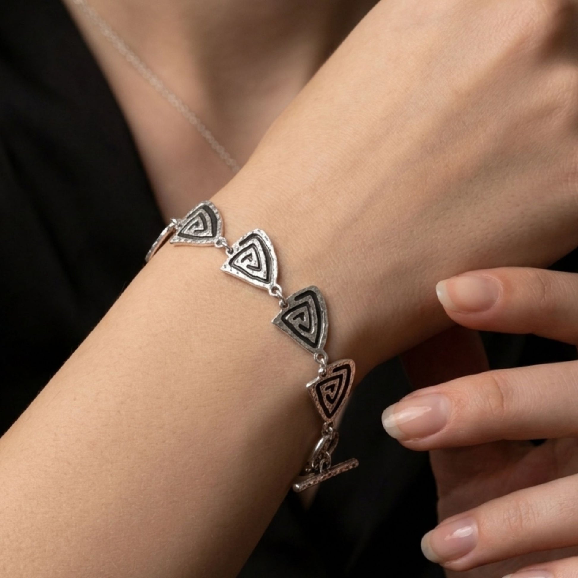 Mujer luciendo pulsera Zamak unisex triángulos espirales concéntricas extensible hipoalergénica Joyería Osnor Zamak